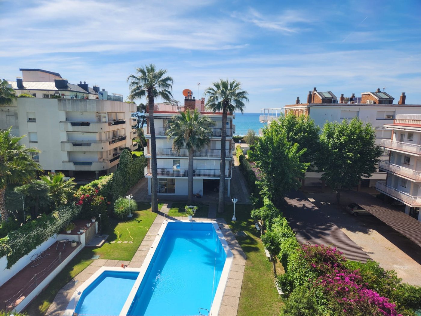 Vista aèria de la piscina comunitària amb palmeres i mar al fons